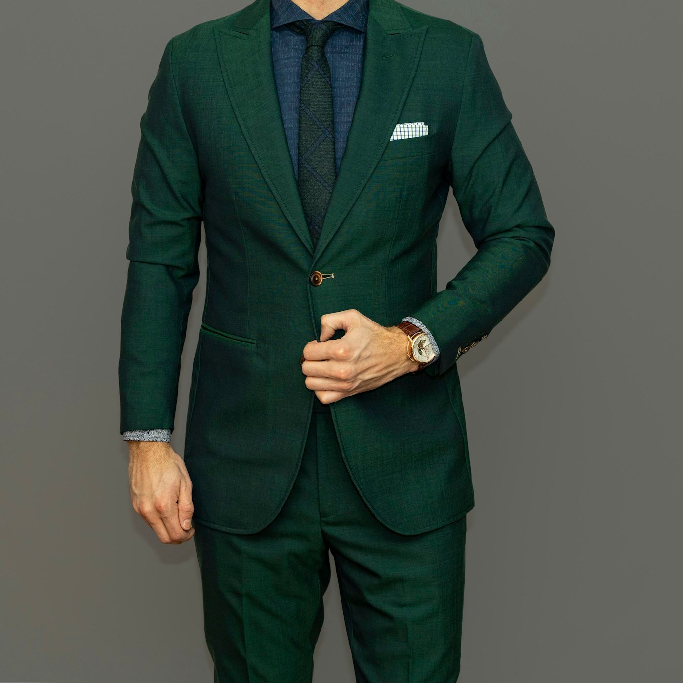 Checked pocket square in the breast pocket of a green suit.