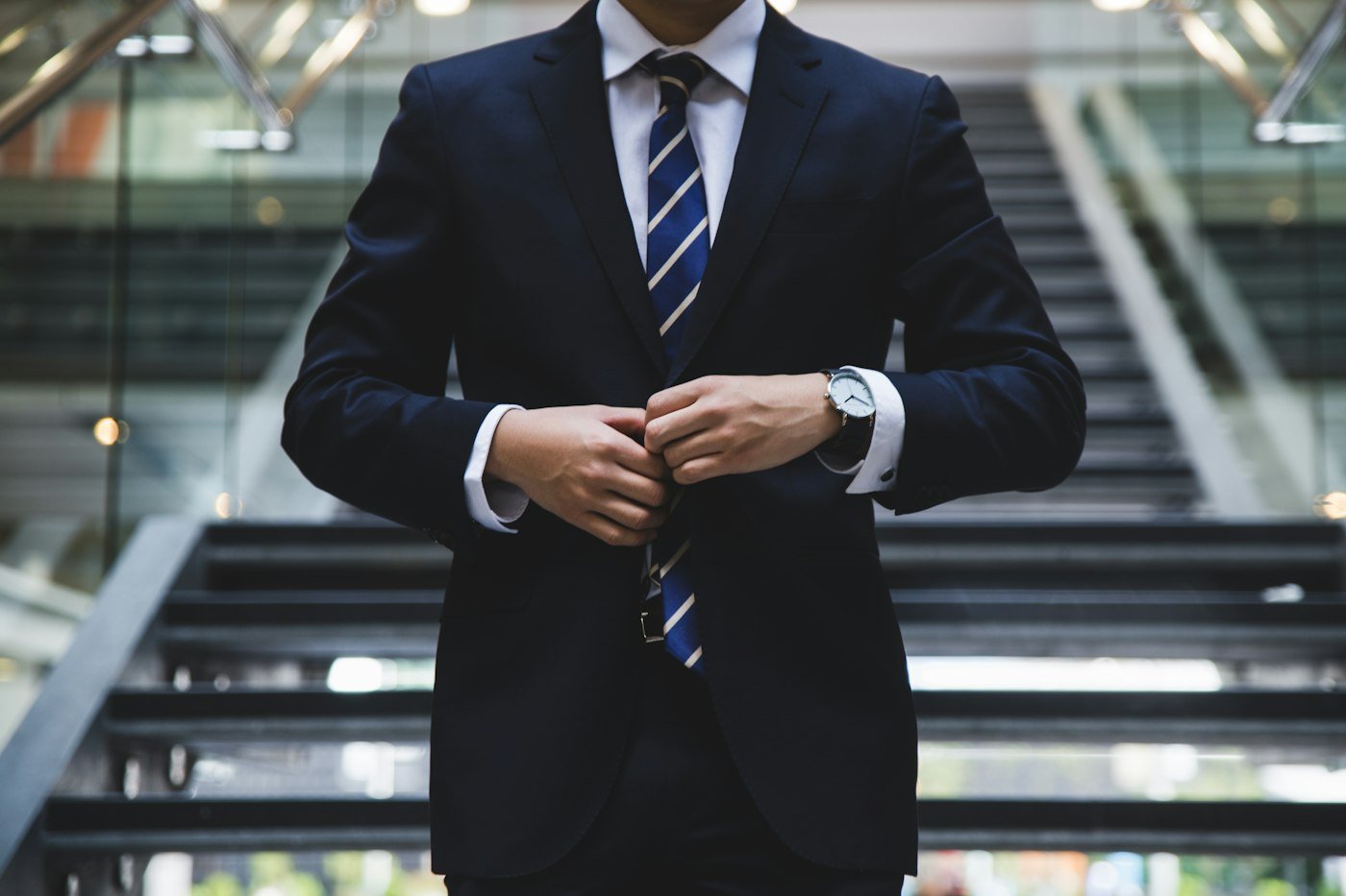Suit cuff beside a striped necktie.